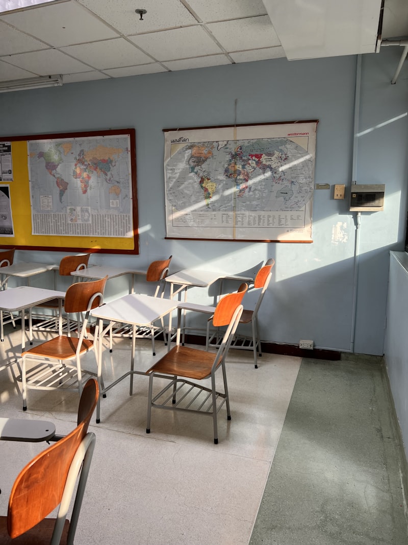 Sala lekcyjna w słońcu, mapy na ścianie i drewniane krzesła
